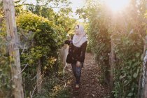 Mujer joven vistiendo en hijab admirando plantas - foto de stock