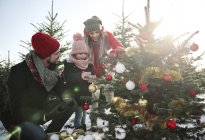 Girl and parents looking at baubles on forest christmas tree — Stock Photo