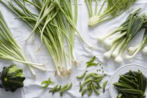 Свежие зеленые овощи на белой скатерти — стоковое фото