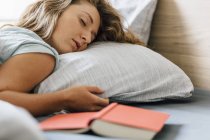 Молодая женщина спит с книгой на кровати — стоковое фото