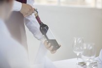 Serveur tenant une bouteille de vin — Photo de stock