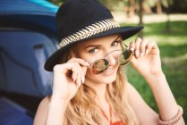 Portrait of young boho woman holding sunglasses at festival — Stock Photo