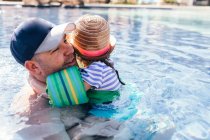 Father and daughter in outdoor swimming pool, daughter hugging father — Stock Photo