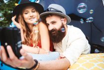 Junges Boho-Paar liegt im Zelt und macht Selfie auf Festival — Stockfoto