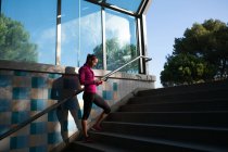 Молодая женщина на лестнице с помощью смартфона — стоковое фото