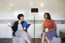 Дві бізнес-леді сидять в зручних стільцях в офісі — стокове фото