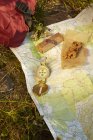 Close up of compass with map and energy bar lying on grass — Stock Photo