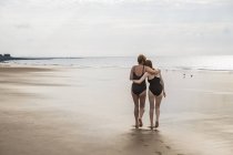 Вид ззаду мати і дочка обіймаються на пляжі — стокове фото
