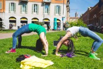 Women doing hand stand with arched back, Milan, Italy — Stock Photo