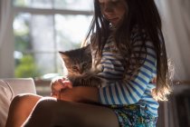 Vista lateral da menina sentada com o gatinho no colo — Fotografia de Stock