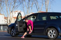 Молода жінка в машині зав'язує шнурки на тренувальному взутті — стокове фото