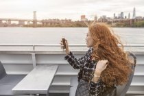 Young businesswoman on passenger ferry deck taking smartphone selfie — Stock Photo