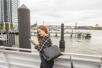 Giovane donna d'affari sul ponte dei traghetti utilizzando smartphone, New York, Stati Uniti — Foto stock