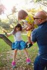 Pai e filhas brincando ao ar livre, filhas sentadas na árvore — Fotografia de Stock