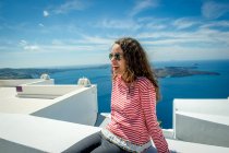 Ragazza rilassante sul muro con il mare sullo sfondo, Santorini, Kikladhes, Grecia — Foto stock