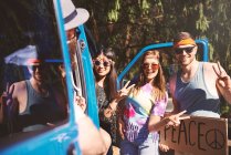 Young boho hitchhikers with peace sign by recreational van — Stock Photo