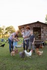 Familie auf dem Bauernhof, umgeben von Hühnern, Mutter und Tochter halten Tablett mit frischen Eiern — Stockfoto