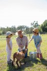 Madre e due bambini in fattoria, bottiglia di alimentazione capra giovane — Foto stock
