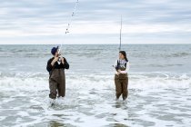 Young couple in waders fishing in water — Stock Photo