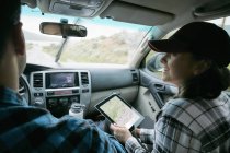 Pareja en coche y mujer sosteniendo tableta digital con mapa - foto de stock
