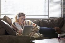 Mujer usando tableta digital en sofá - foto de stock