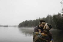 Пара, загорнутий у ковдру цілується біля озера, Банкрофт, Канада, Північна Америка — стокове фото