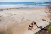 Jeune femme s'échauffant sur la plage, Carcavelos, Lisboa, Portugal, Europe — Photo de stock