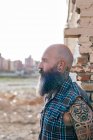 Hipster mâle mature tatoué par un mur de bâtiment démoli — Photo de stock