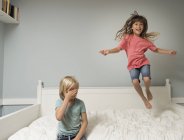 Mädchen in der Luft springt auf Bett im Schlafzimmer — Stockfoto