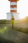 Jovem corredor feminino correndo na pista de terra costeira ao pôr do sol — Fotografia de Stock