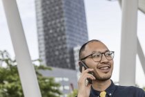 Бізнесмен посміхається і розмовляє на смартфоні на відкритому повітрі — стокове фото