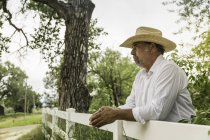 Mature man in cowboy hat looking out from ranch fence, Bridger, Montana, USA — Stock Photo