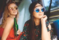 Two young boho women wearing sunglasses in recreational van — Stock Photo