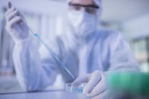 Laborarbeiter verwendet lange Pipette, um Flüssigkeit in Petrischale zu übertragen — Stockfoto