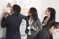 Empresários colando notas para quadro branco — Fotografia de Stock