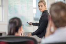Over the shoulder view of young female office worker giving whiteboard presentation — Stock Photo