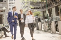 Junge Geschäftsfrau und Geschäftsleute mit Kaffee zum Mitnehmen schlendern auf Bürgersteig — Stockfoto