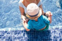Mãe e filho jovem na piscina ao ar livre, vista elevada, seção meio — Fotografia de Stock