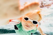 Мальчик плавает под водой в бассейне, с видом на море — стоковое фото