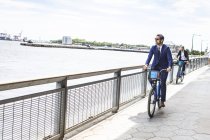 Two businessmen cycling on waterfront path — Stock Photo