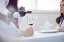 Garçom em restaurante, derramando vinho para comensais, seção meio — Fotografia de Stock