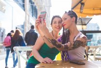 Mujeres en el descanso de la ciudad en la cafetería al aire libre tomando selfie, Milán, Italia - foto de stock