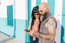 Reifes Hipster-Paar schaut auf Gehweg aufs Smartphone — Stockfoto