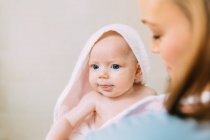 Portrait of Mother holding baby girl wrapped in towel — Stock Photo