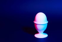 Ovo em copo de ovo no fundo azul — Fotografia de Stock