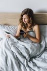 Jovem mulher ler revista na cama — Fotografia de Stock