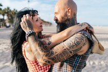 Зрелая татуированная пара хипстеров лицом к лицу на пляже, Валенсия, Испания — стоковое фото