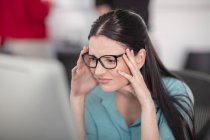 Jovem trabalhadora de escritório estressada olhando para o computador desktop — Fotografia de Stock