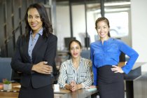 Portrait de trois femmes d'affaires dans un bureau décloisonné — Photo de stock