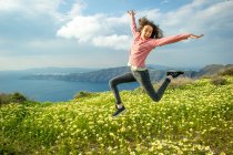 Mädchen hüpft mitten in der Luft über Blumen, Santorini, Kikladhes, Griechenland — Stockfoto
